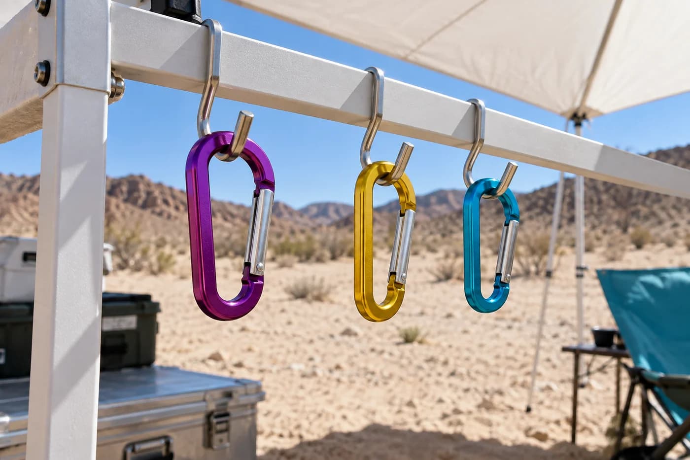 Violet, yellow and cyan metal clips hanging separately in a row on hooks on a white camping rack