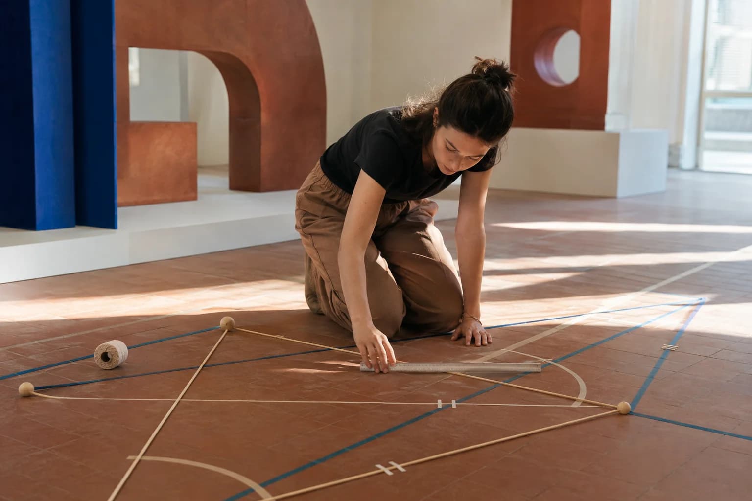 Un apprenant adulte mesure une grande installation géométrique au sol au lieu de juger les formes à vue